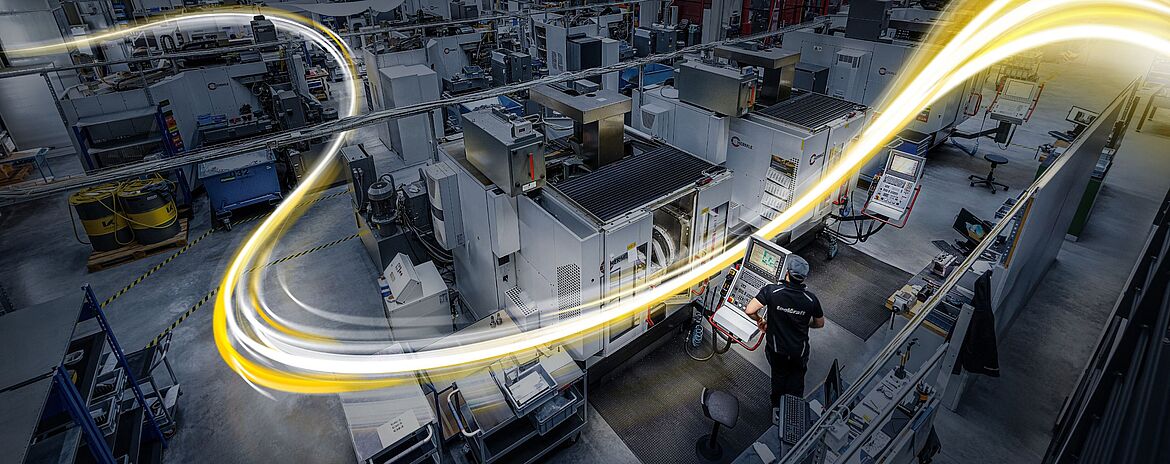 Gelb-weißer Lichtschweif durch eine Halle mit Zerspanungsmaschinen bei toolcraft